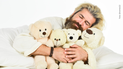 Hombre abrazando unos peluches.