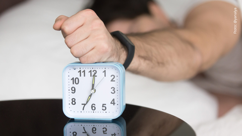Hombre somnoliento y molesto apagando la alarma.