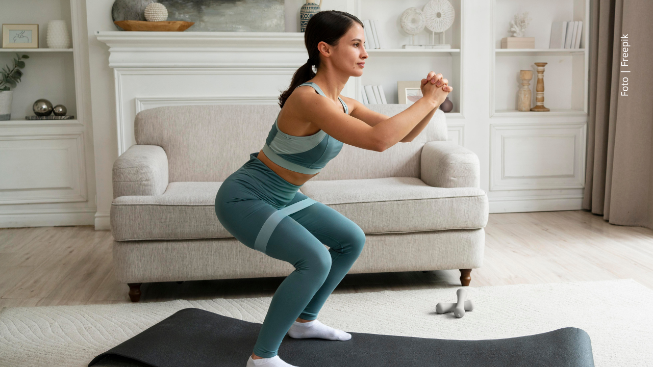 Mujer practica ejercicios en la sala de su casa.