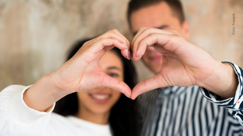 Pareja de novios haciendo haciendo un corazón con la mano.