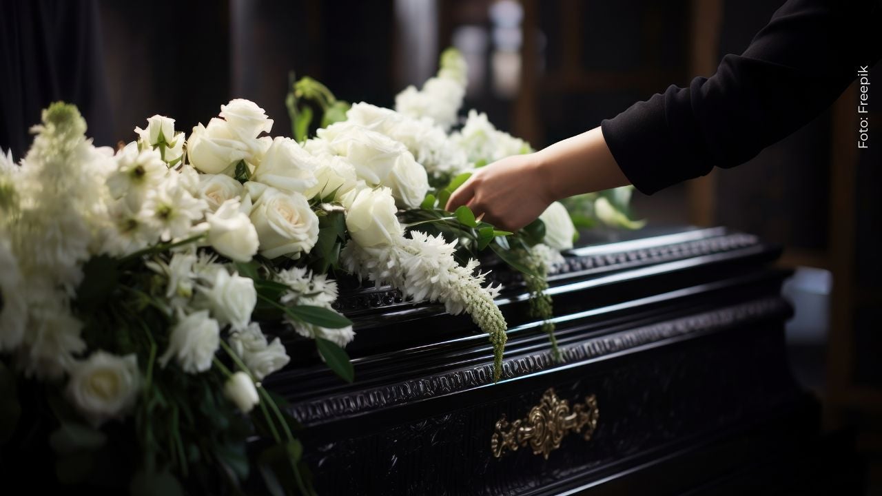 Imagen de un ataúd adornado con un ramo de rosas blancas