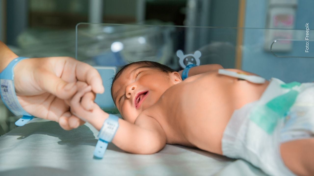 Bebé recién nacido sujetando la mano del médico